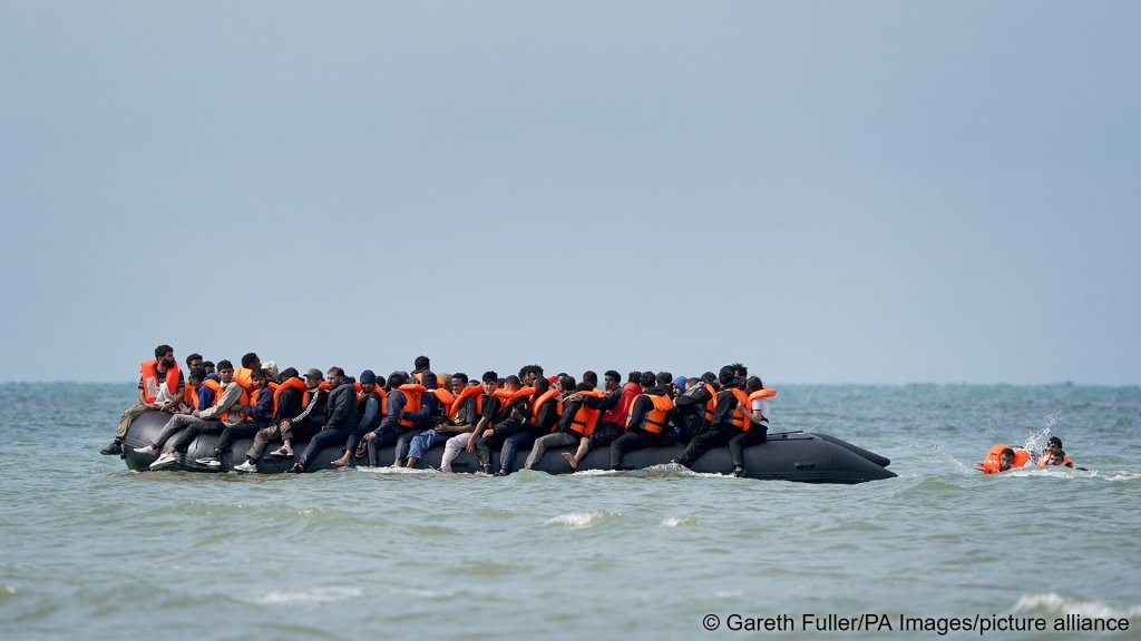 Two people swimming towards an overcrowded dinghy off the coast of Equihen-Plage, France, on July 22, 2026 | Photo: picture alliance