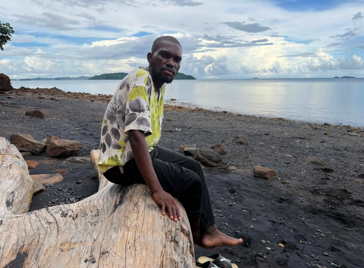Alexis sitting by the water's edge, a few meters away from the Tsoundzou 2 camp | Photo: InfoMigrants