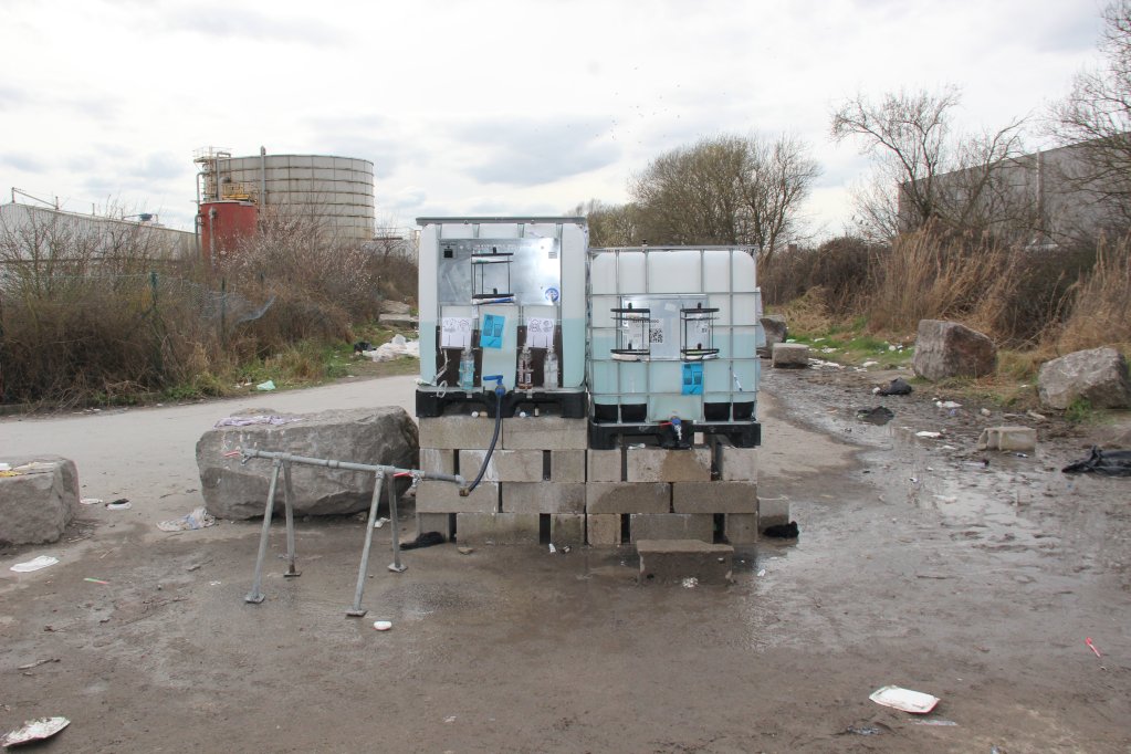 Se brosser les dents, nettoyer la boue de ses pieds, cuisiner ou boire... L'eau potable apportée chaque jour par l'association Roots sur les camps de Loon-Plage s'avère indispensable aux migrants. Crédit : Arnaud Stoerkler