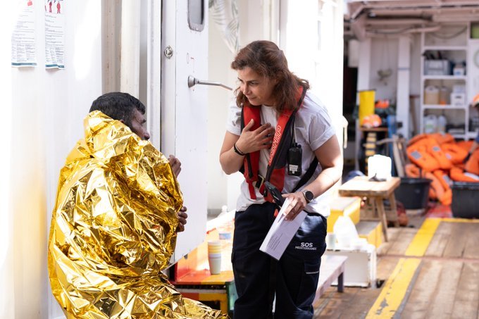 A crew member on board Ocean Viking, operated by SOS Mediterranée talks to one of the 75 migrants they rescued. The group reportedly spend five days and four nights at sea and some were suffering from dehydration | Source: X @SOSMedIntl