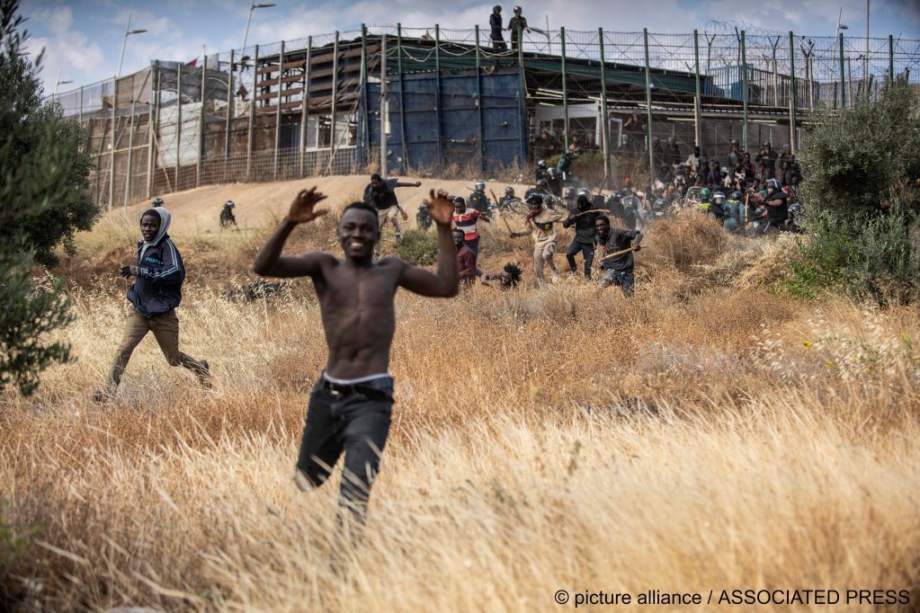 Migrants run away from the border fence after crossing into the Spanish enclave of Melilla, June 24, 2022 | Photo: Javier Bernardo/AP/picture-alliance