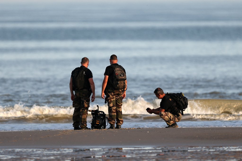 French officials are pictures examining an abandoned boat engine presumed to belong to a migrant boat near Boulogne-sur-Mer in early July 2025 | Photo: Reuters