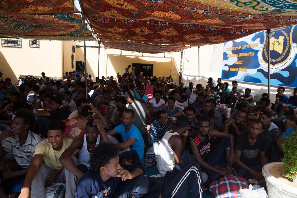 File photo used for illustration: Migrants sit at Njila detention center near Tripoli, Libya | Photo: ANSA