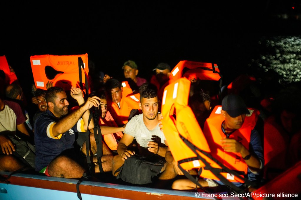 Migrants, mostly from Tunisia, put on life jackets in a wooden boat as they are assisted by Spanish NGO Open Arms crew members during a rescue operation south of the Italian island of Lampedusa in the Mediterranean sea, Saturday, Aug. 6, 2022 | Photo: Francisco Seco /AP Photo/ picture alliance