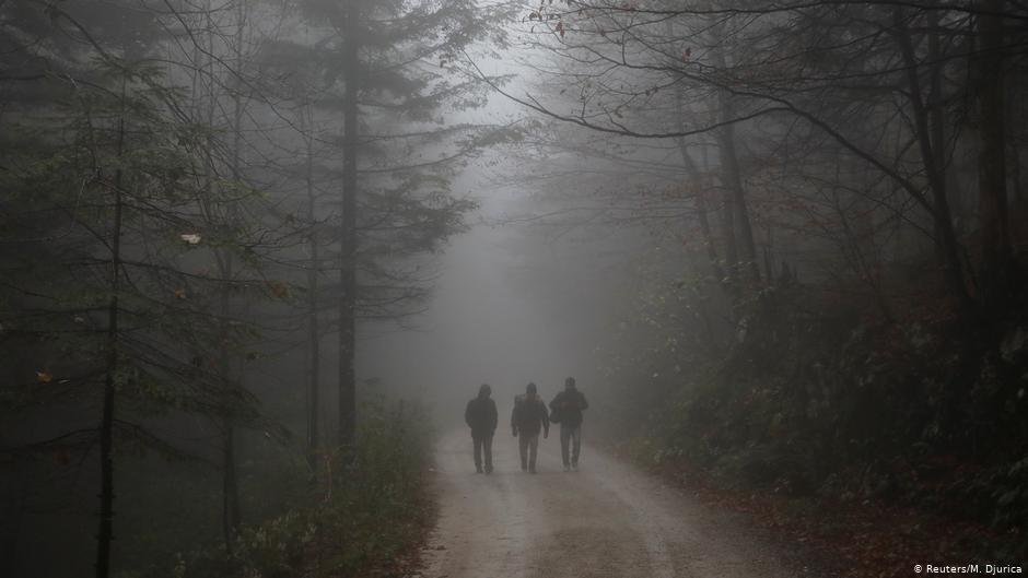 ثلاثة أشخاص يمشون عبر الغابات بالقرب من مخيم فوتشياك | الصورة: رويترز / م. دجوريكا  