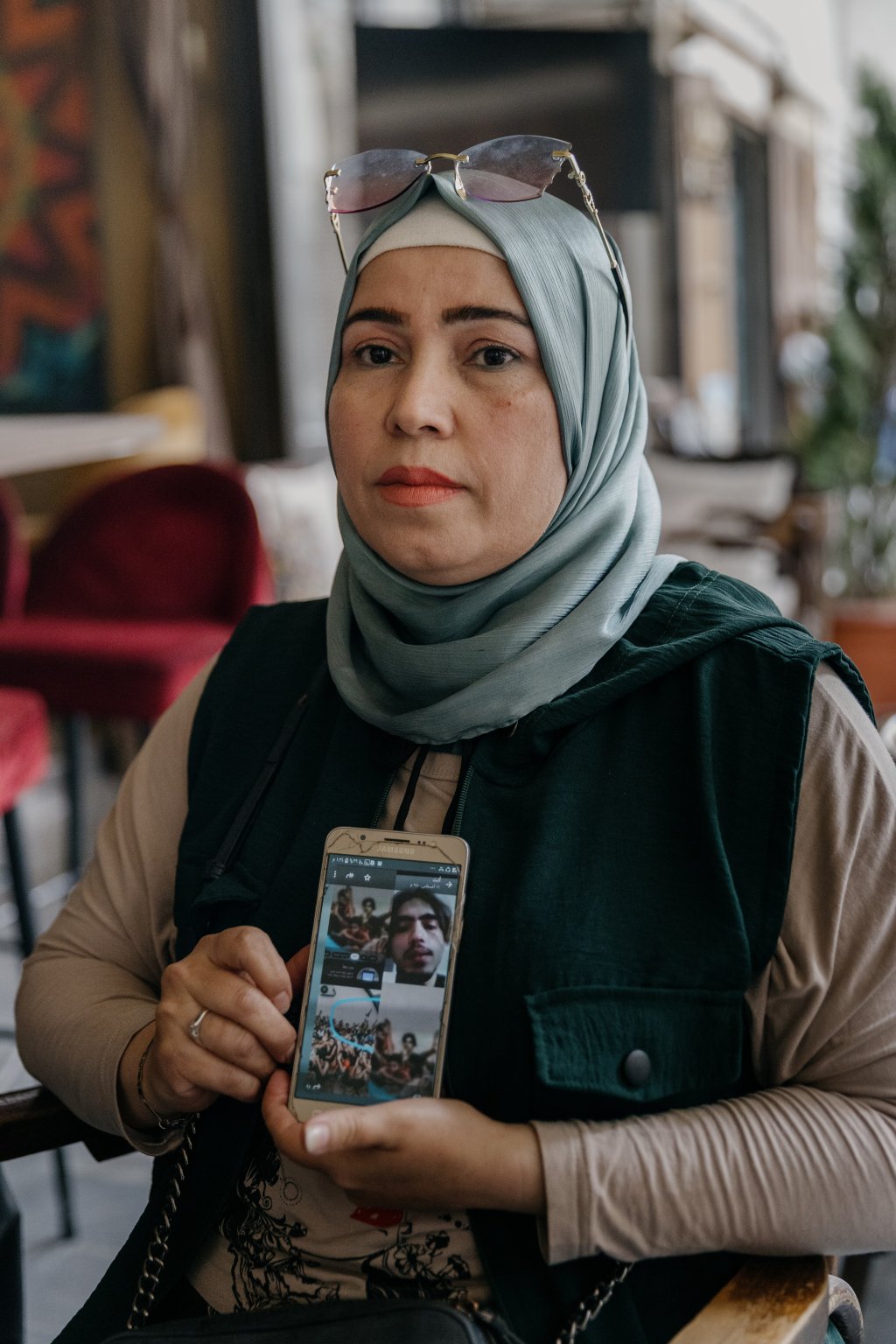 Fatima Mohammad Kaer Tru is desperately searching for her son, who disappeared in Libya in March 2024. She holds her phone in her hands, showing a photo of her son found on social media, in a Libyan prison. Damascus, Syria, September 25, 2025 | Photo: Valentina Camu/Divergence