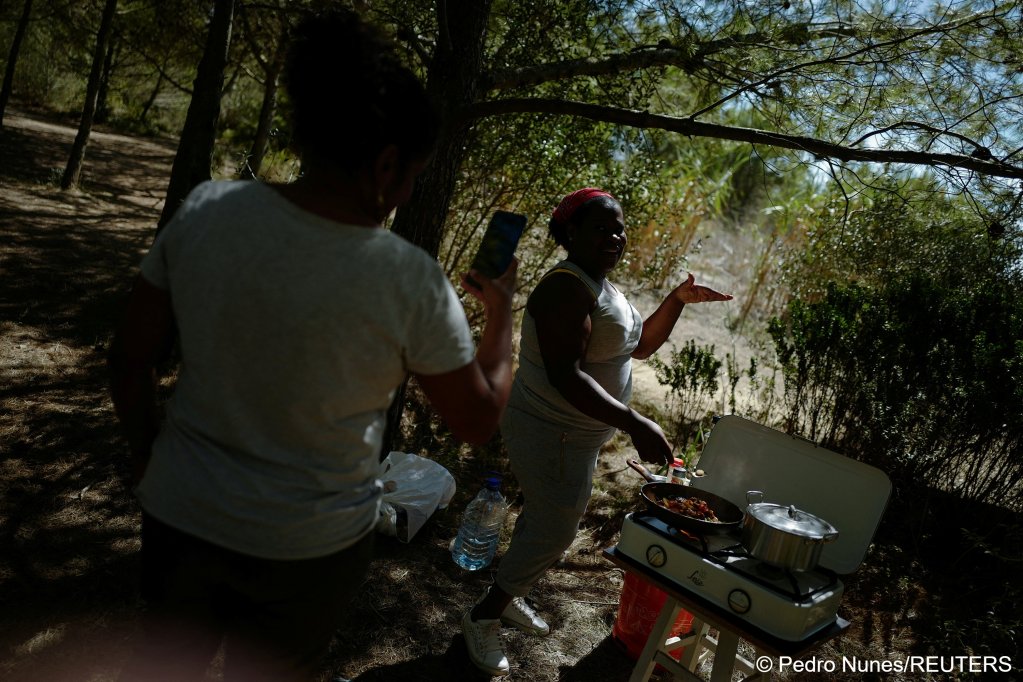 Andreia Costa, 50, from Sao Paulo, Brazil, makes a video for the social media account of Marcia Leandro, 43, from Rio de Janeiro, Brazil (R), at the improvised campsite in a field where they live in Carcavelos, in Cascais, Portugal, September 27, 2023 | Photo: Pedro Nunes / Reuters