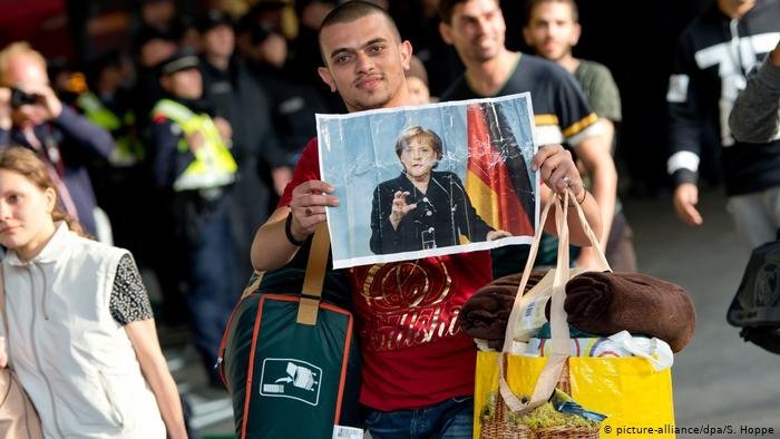 Des demandeurs d’asile arrivant à l’aéroport de Munich, remerciant Angela Merkel pour avoir ouvert les frontières du pays. Crédit : Picture alliance