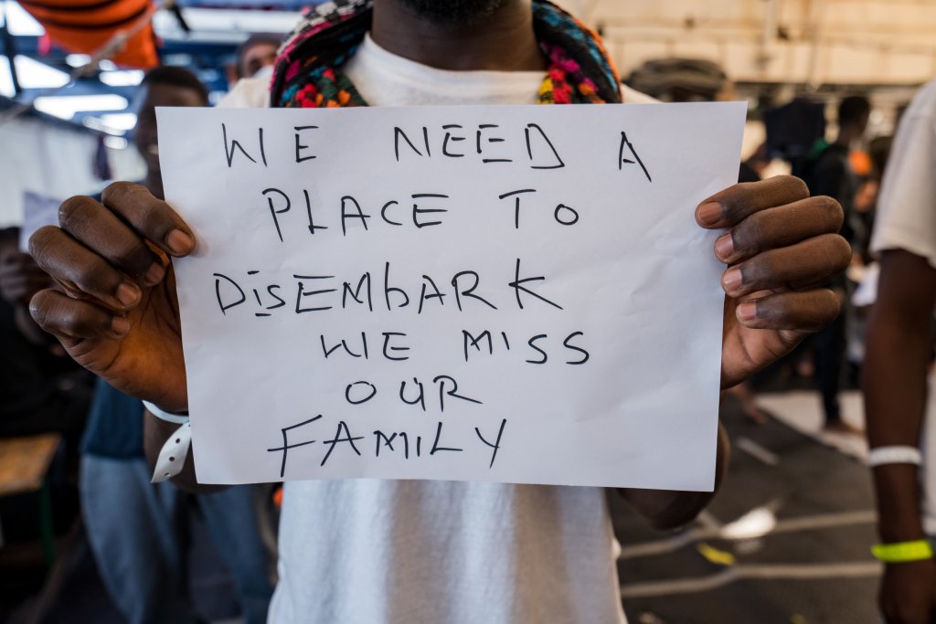 A rescued migrant holds up a sign on the Humanity 1 rescue ship in November 2022. | Photo credit: Camilla Kranzusch / SOS Humanity