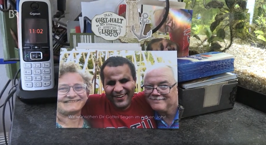 A piture showing Saho (center) with his host parents Gisela and Gerhard Zierer | Source: Screenshot video report BR (Bayerischer Rundfunk)