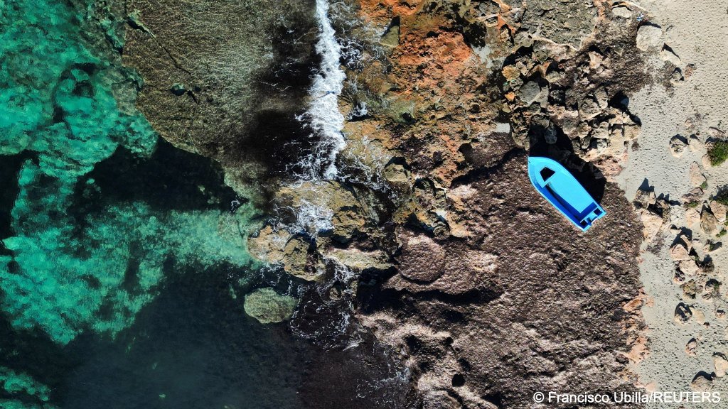 A drone view of a discarded boat used by migrants to reach Mallorca rests on Es Caragol beach in the south of the Balearic island, in Santanyi, Mallorca, Spain, November 20, 2025 | Photo: Francisco Ubilla / Reuters