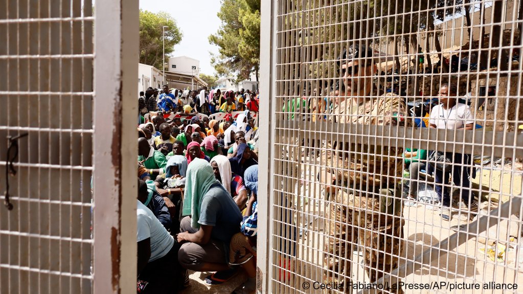 An army officer closes the gate of a migrant a reception center as migrants sit inside, on the Sicilian island of Lampedusa, southern Italy, Saturday, Sept. 16, 2023. | Photo: Cecilia Fabiano/LaPresse via AP