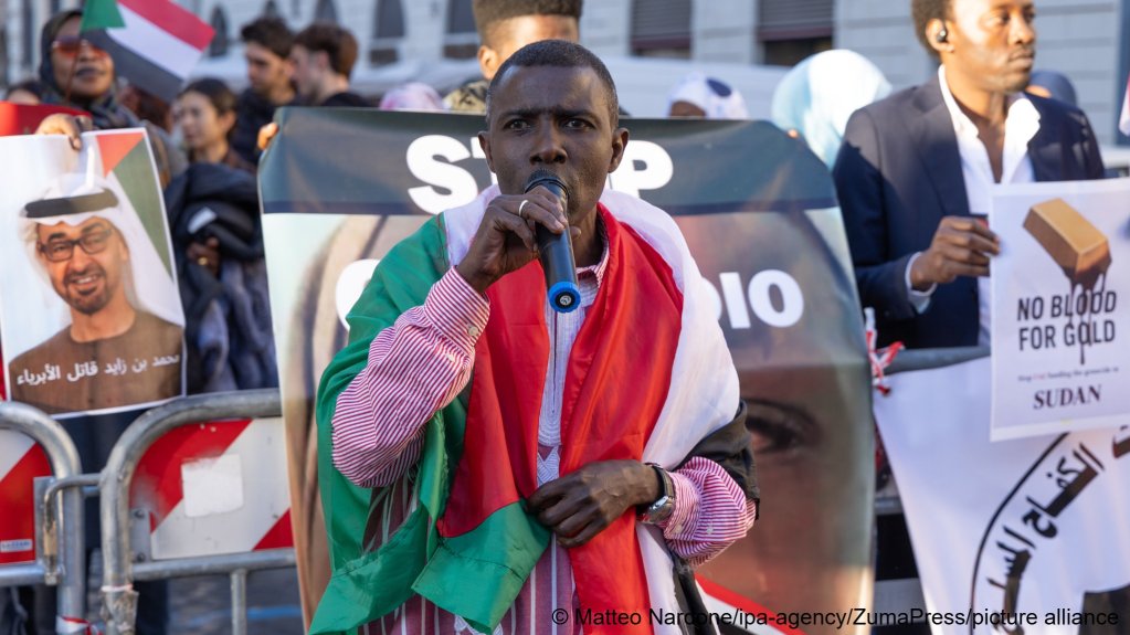 File photo used as illustration: A man with a Sudanese flag wrapped around his shoulders speaking into a microphone during a protest against the war in Sudan in Piazza Santi Apostoli in Rome on November 12, 2025 | Photo: picture alliance