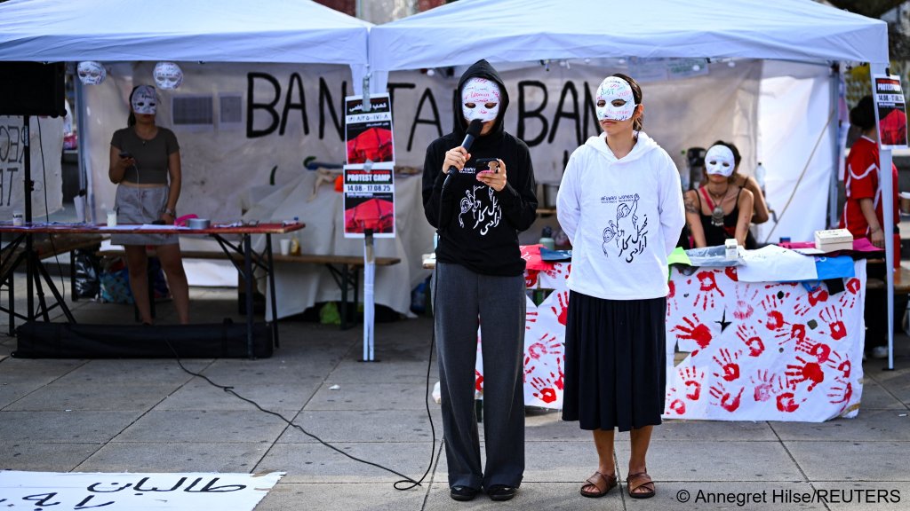 Activists wearing a face mask and speaking for a vigil at a protest camp on the Alexanderplatz to express solidarity with Afghans living under Taliban rule, four years after the group returned to power in Berlin, Germany August 15, 2025 | Photo: REUTERS/Annegret Hilse
