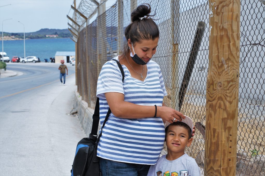 أمام المخيم المؤقت على جزيرة ليسبوس تقف طالبة اللجوء الحامل في شهرها التاسع مع ابنها. الصورة: دانا البوز