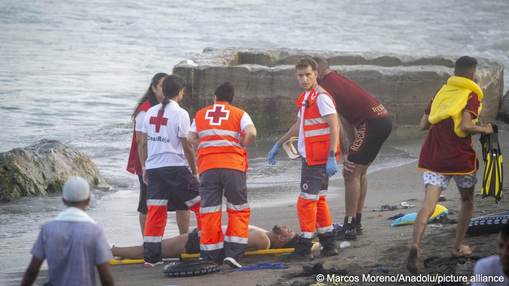 Red cross workers surround a person that has collapsed on a beach in Ceuta on July 30, 2026 | Photo: Marco Moreno / Anadolu / picture alliance