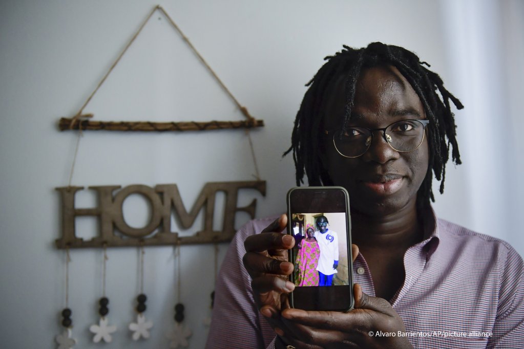Mbaye Babacar Diouf, 33, displays a photo of himself with his Senegalese mother on a phone| Photo: Alvaro Barrientos / AP Photo / picture-alliance