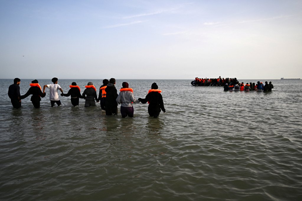 File photo: A group of migrants wade through the water to board an inflatable dinghy before leaving the coast of northern France in an attempt to cross the English Channel | Photo: Dylan Martinez / Reuters