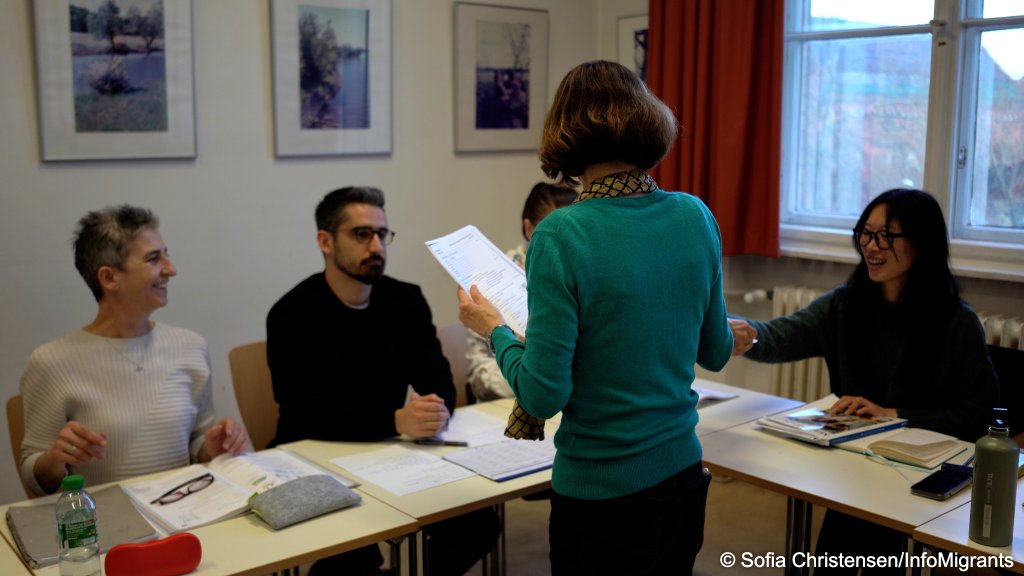 German teacher Mira Köller hands an exercise&nbsp;sheet to students attending an integration course. Berlin, March 25, 2026 | Photo: Sofia Christensen / InfoMigrants
