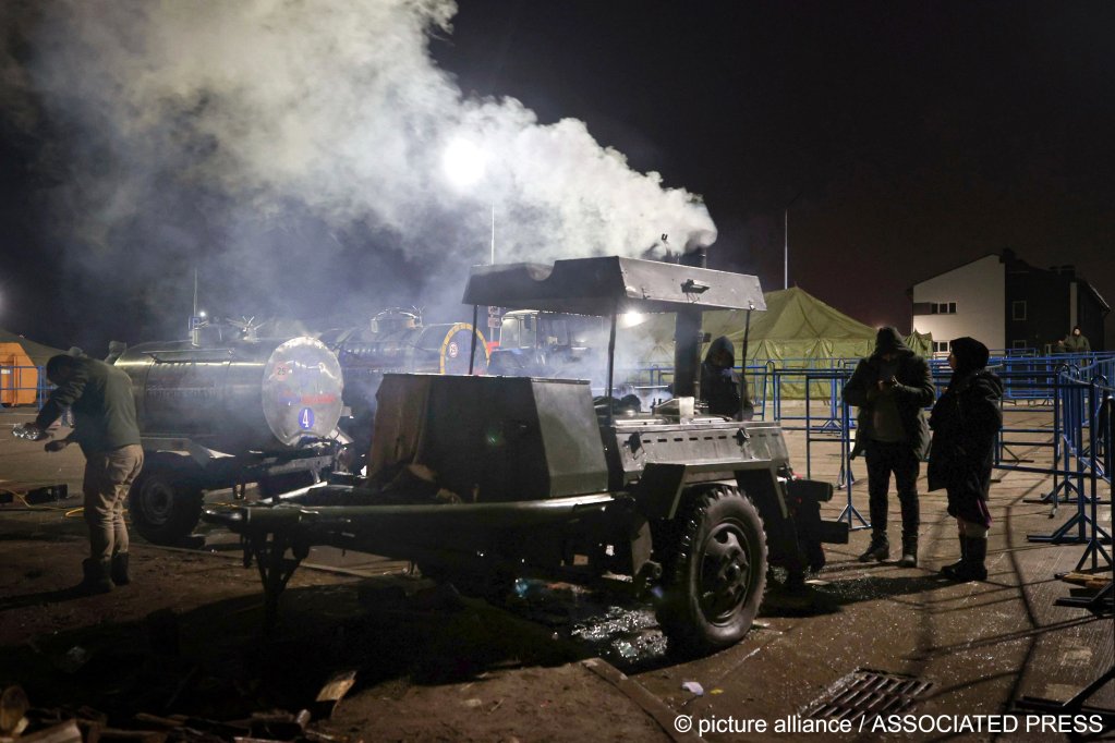 Migrants stand around field kitchen waiting to get meal at a logistics center at the checkpoint 'Kuznitsa' at the Belarus-Poland border near Grodno, Belarus on November 22, 2021 | Photo: Maxim Guchek/BelTA/AP