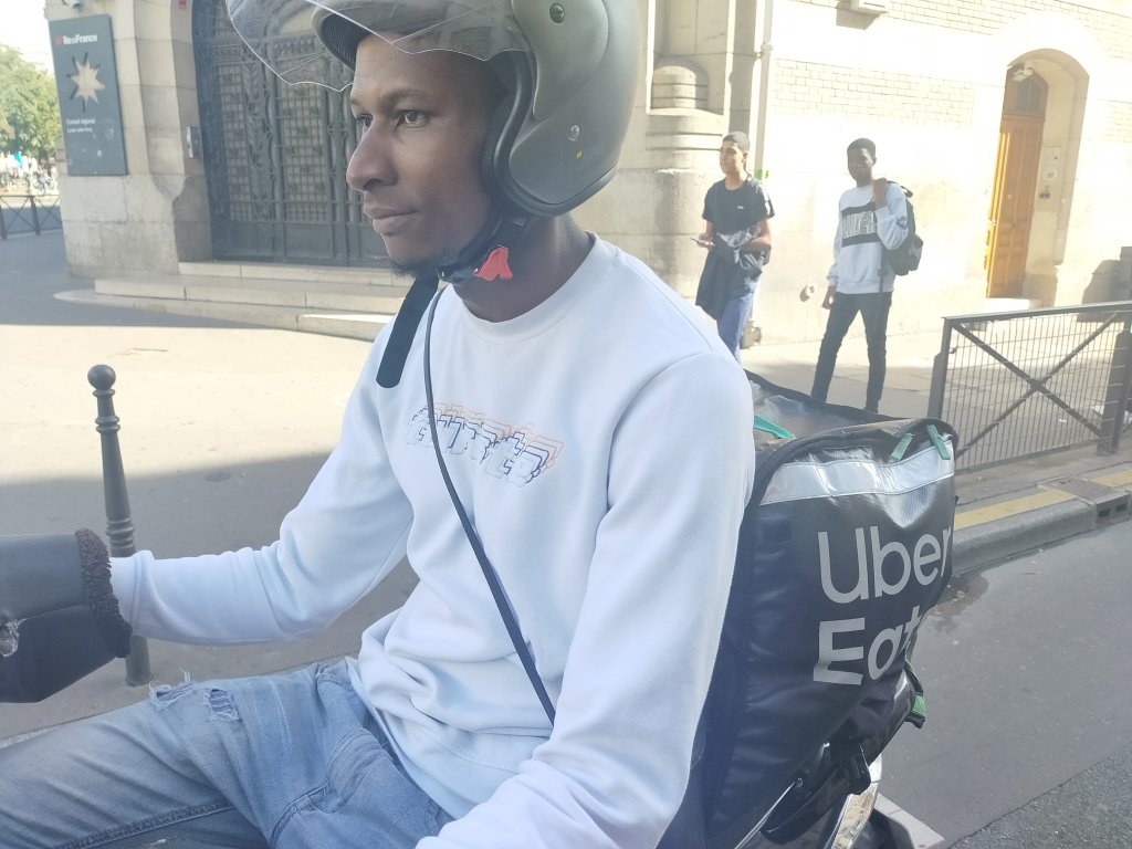 Aboubacar Cissé sur son scooter équipé d'un sac isotherme, dont il n'a désormais plus l'utilité. Crédit : InfoMigrants