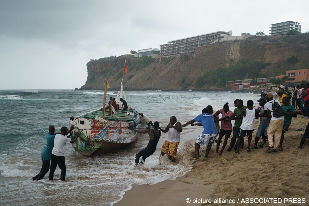 People work together to pull the capsized boat ashore at the beach where several people were found dead in Dakar, Senegal on Monday, July 24, 2023 | Photo: Leo Correa/AP/picture-alliance