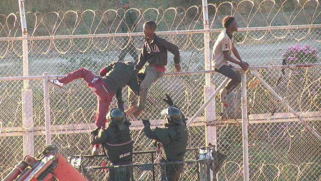 Des migrants traversant la barrière grillagée entre le Maroc et l'enclave espagnole de Ceuta, le 26 juillet 2018. Crédit : Reuters