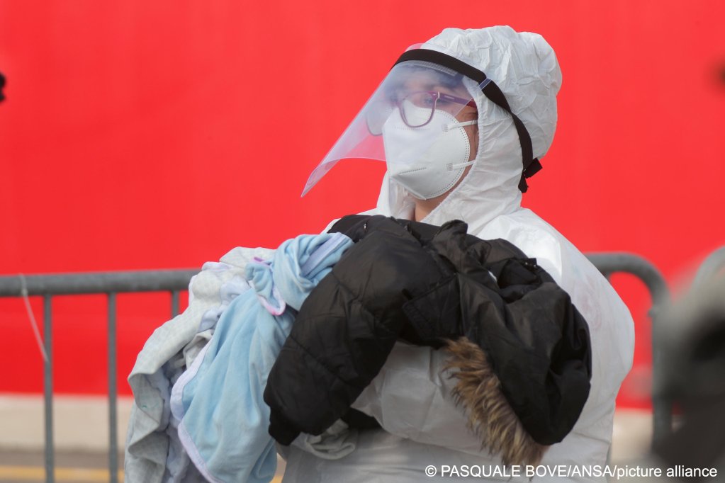 From file: A health worker carries a small child migrant under a coat. | Photo credit: Pasquale Bove/picture alliance / ZUMAPRESS.com