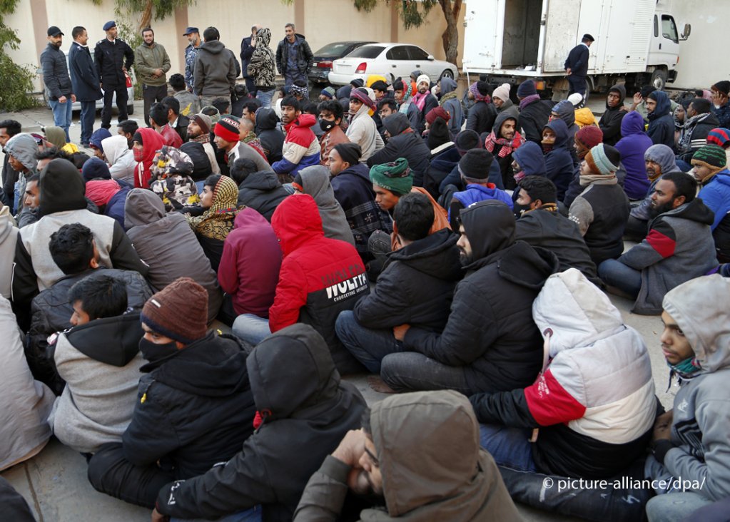 مهاجرون محتجزون يجلسون أمام قوات الأمن بعد إعادتهم إلى ليبيا بعد محاولة عبور البحر الأبيض المتوسط 