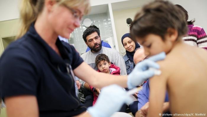 From file: A refugee child receives a vaccination shot in Germany. Health experts say that a thorough vaccination protocol is needed to improve migrant health | Photo: Picture Alliance