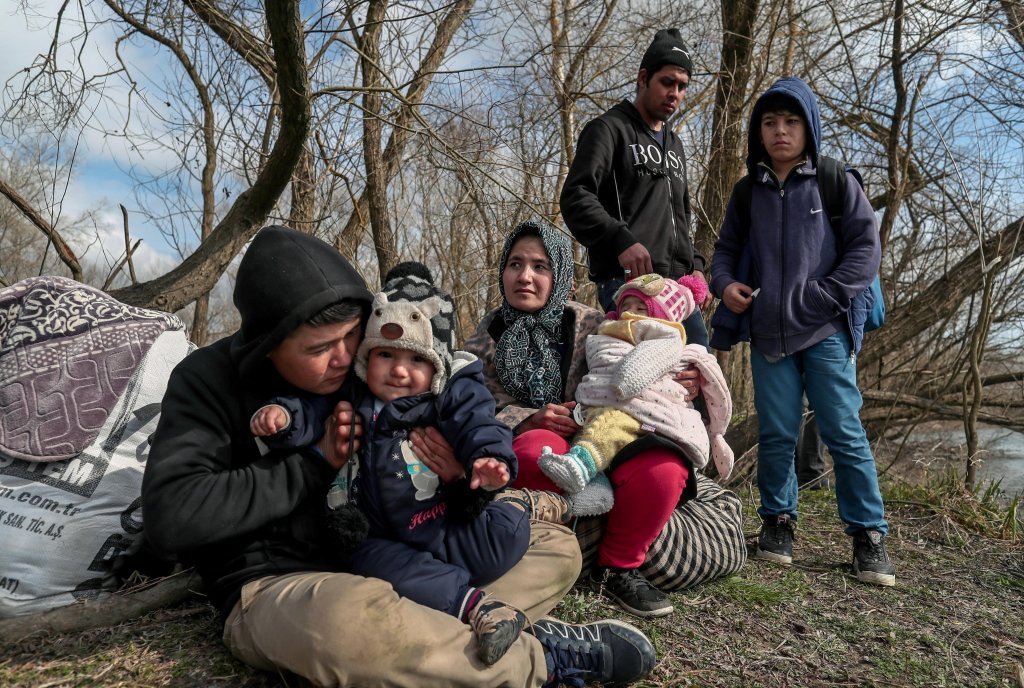 مجموعة من المهاجرين مع أطفالهم يستريحون على ضفة نهر  إفروس على الحدود التركية اليونانية بالقرب من أدرنة، تركيا