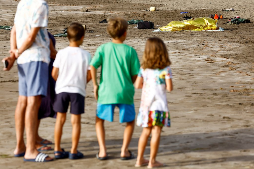 Des touristes regardent un migrant qui vient d'arriver à Grande Canarie, le 18 juillet 2024. Crédit : Reuters