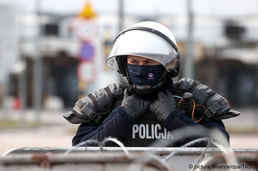 A Polish police officer is seen behind a barbed wire fence at Kuznica Bialostocka-Bruzgi border crossing on the Belarusian-Polish border on November 22, 2021 | Photo: Sergei Bobylev/TASS/dpa/picture-alliance