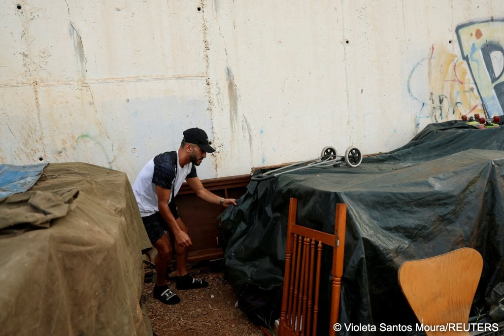 Ceuta resident Bilal Kadur lifts a tarp while trying not to wake sleeping migrant children he told reporters he is sheltering and watching over | Photo: Violeta Santos Moura / Reuters