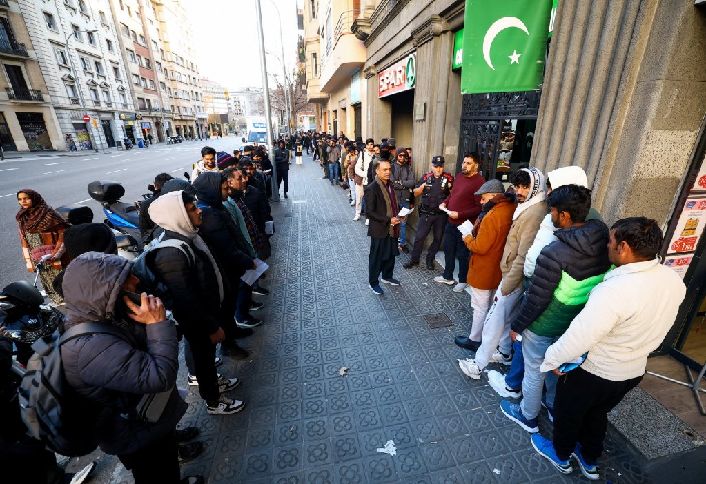 People queue outside Pakistan’s consulate in Barcelona to apply for criminal record certificates, a document required for the migrant regularization program | Photo: Albert Gea / Reuters