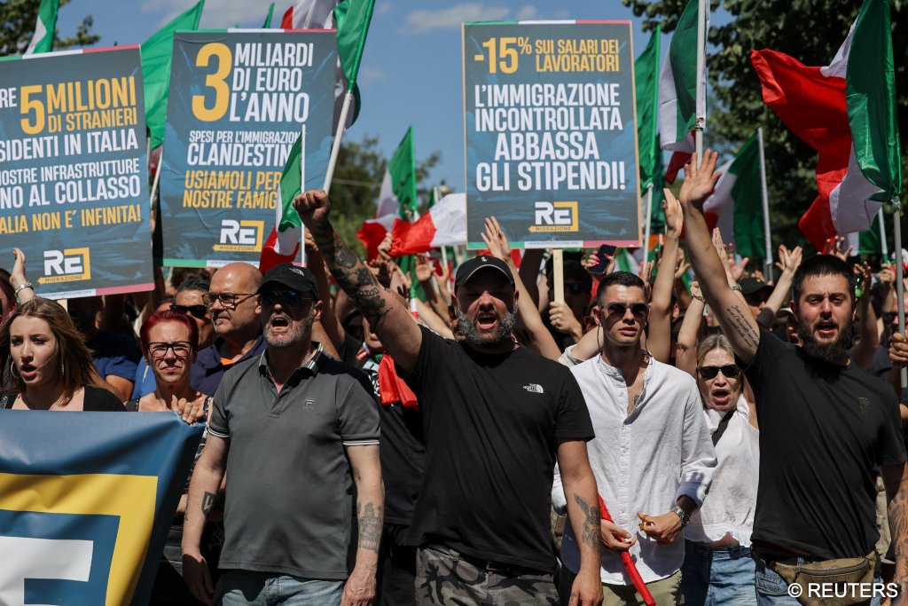 Demonstrators chant and hold placards making claims about the cost of immigration and its effect on workers’ wages during a “remigration” march in Rome | Photo: Francesco Fotia / Reuters
