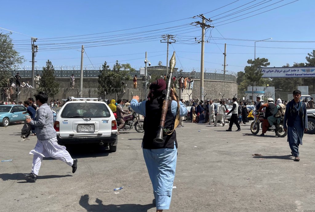 بعض سكان كابول يحاولون تسلق جدار مطار كابول بحضور عناصر طالبان ، 16 أغسطس ، 2021. تصوير رويترز 