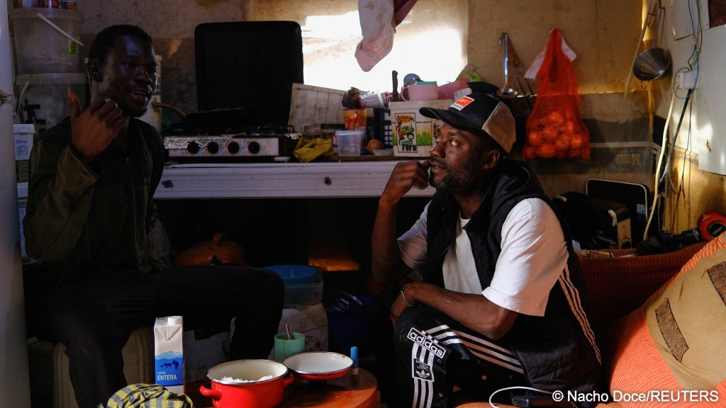 Undocumented migrants from Ghana talk inside a shack in a shanty town near plastic-covered greenhouses in Almeria province, home to Europe’s largest concentration of agricultural greenhouses, in Nijar, Spain | Photo: Nacho Doce / Reuters
