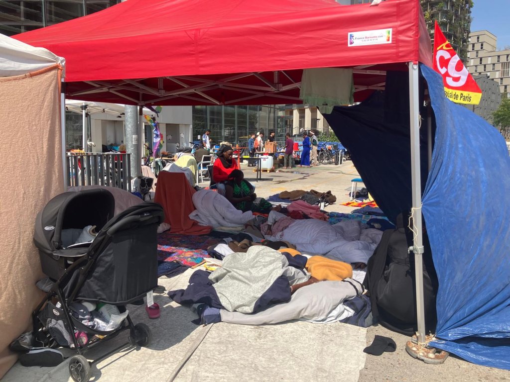 A stroller sits next to the blankets serving as a resting space for families occupying the Samusocial plaza. July 22, 2026, Paris | Photo: InfoMigrants