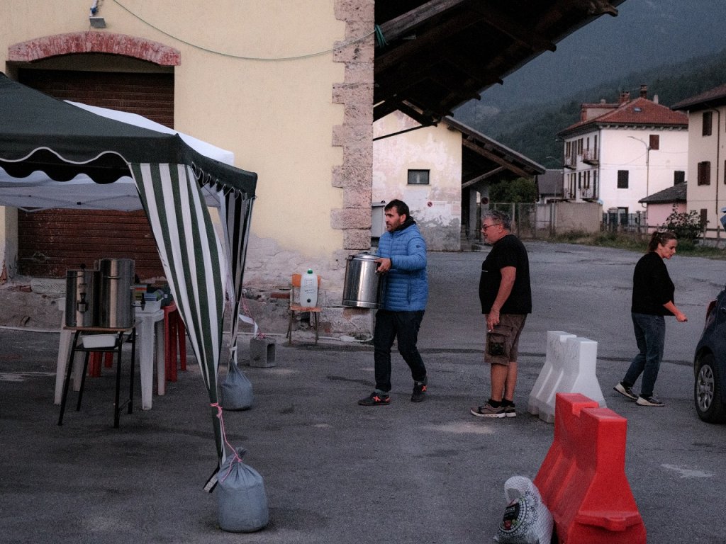 Around 8.45 pm, volunteers bring meals to the parking lot. The meals are prepared in a room equipped with a small kitchen, a few steps away. The stoves are then placed under the canopies before the meals are served | Photo: Jean Kader/Encrage