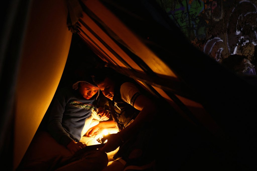 File photo used as illustration: Two young Moroccan migrants listen to music from their cell phones in the Arinaga ravine where they live, on the island of Gran Canaria, Spain | Photo: Borja Suarez / Reuters
