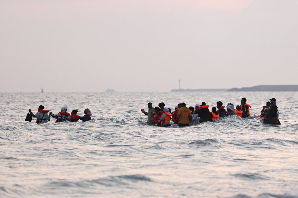 A group of migrants venture into the water from the beach at Petit-Fort-Philippe in Gravelines, near Calais, to reach an inflatable dinghy and cross the English Channel, July 2, 2025 | Photo: Reuters
