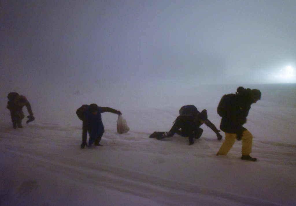 A group of four North African migrants struggle to keep their balance in knee-deep snow as they trek into France at night on February 5, 2021 | Photo: Mehdi Chebil