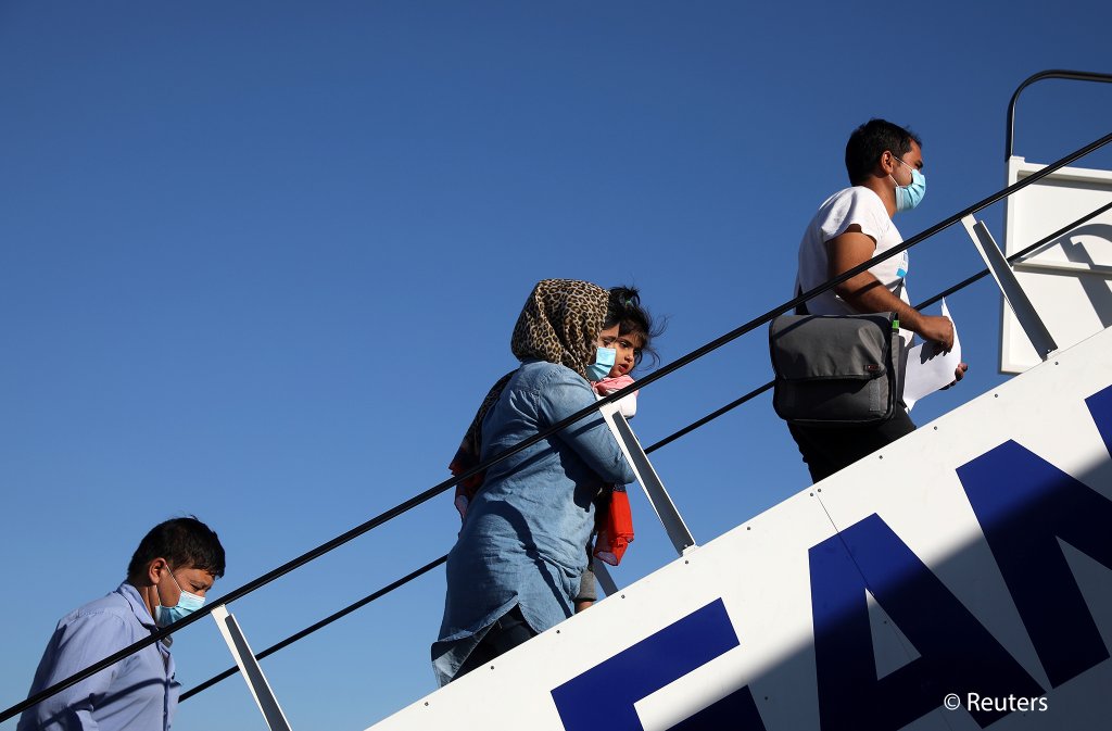 أشخاص يستقلون طائرة تابعة لشركة طيران إيجه نقلت اللاجئين والمهاجرين إلى ألمانيا في إطار برنامج إعادة التوطين الذي تموله المفوضية الأوروبية، من مطار الفثيريوس فينيزيلوس الدولي في أثينا، اليونان يوم 24 يوليو 2020