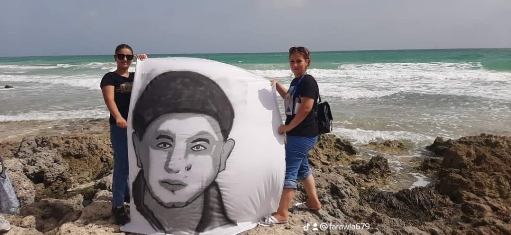 لطيفة الولهازي تحمل صورة أخيها أما البحر بعد جهود كبيرة في العثور على جثمانه. الصورة: خاصة