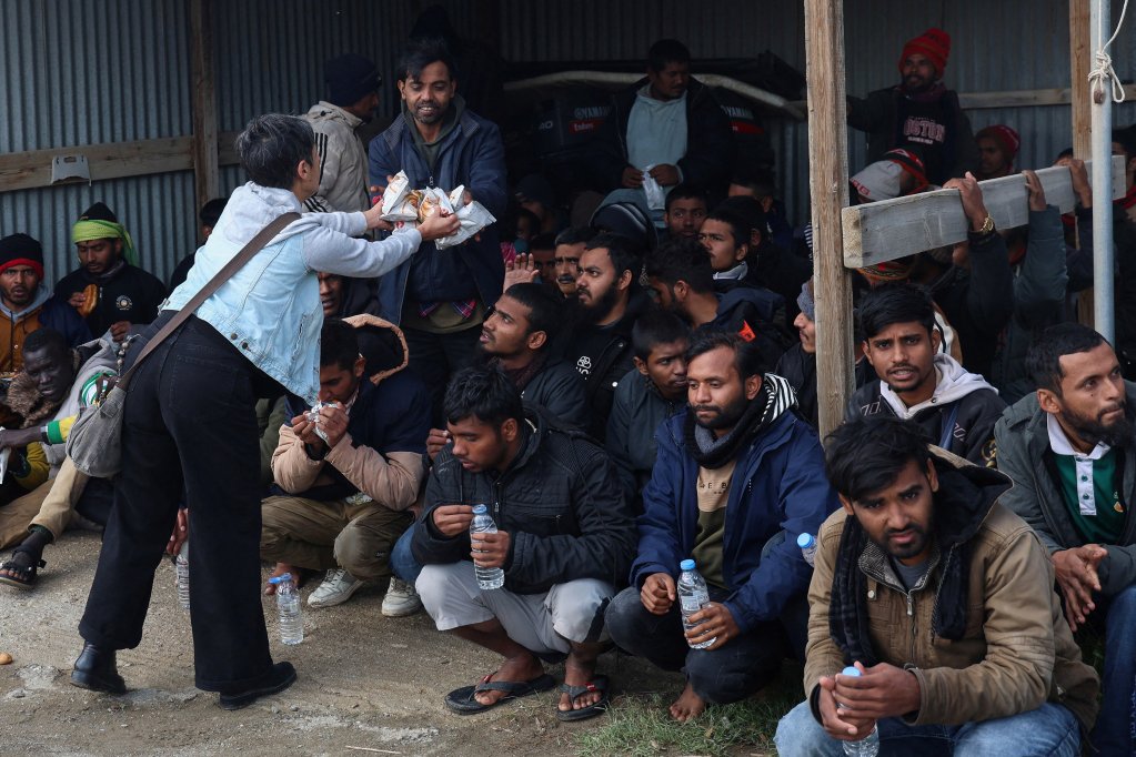 A volunteer hands out food to migrants who survived the boat capsizing off Crete on February 21 | Photo: Reuters
