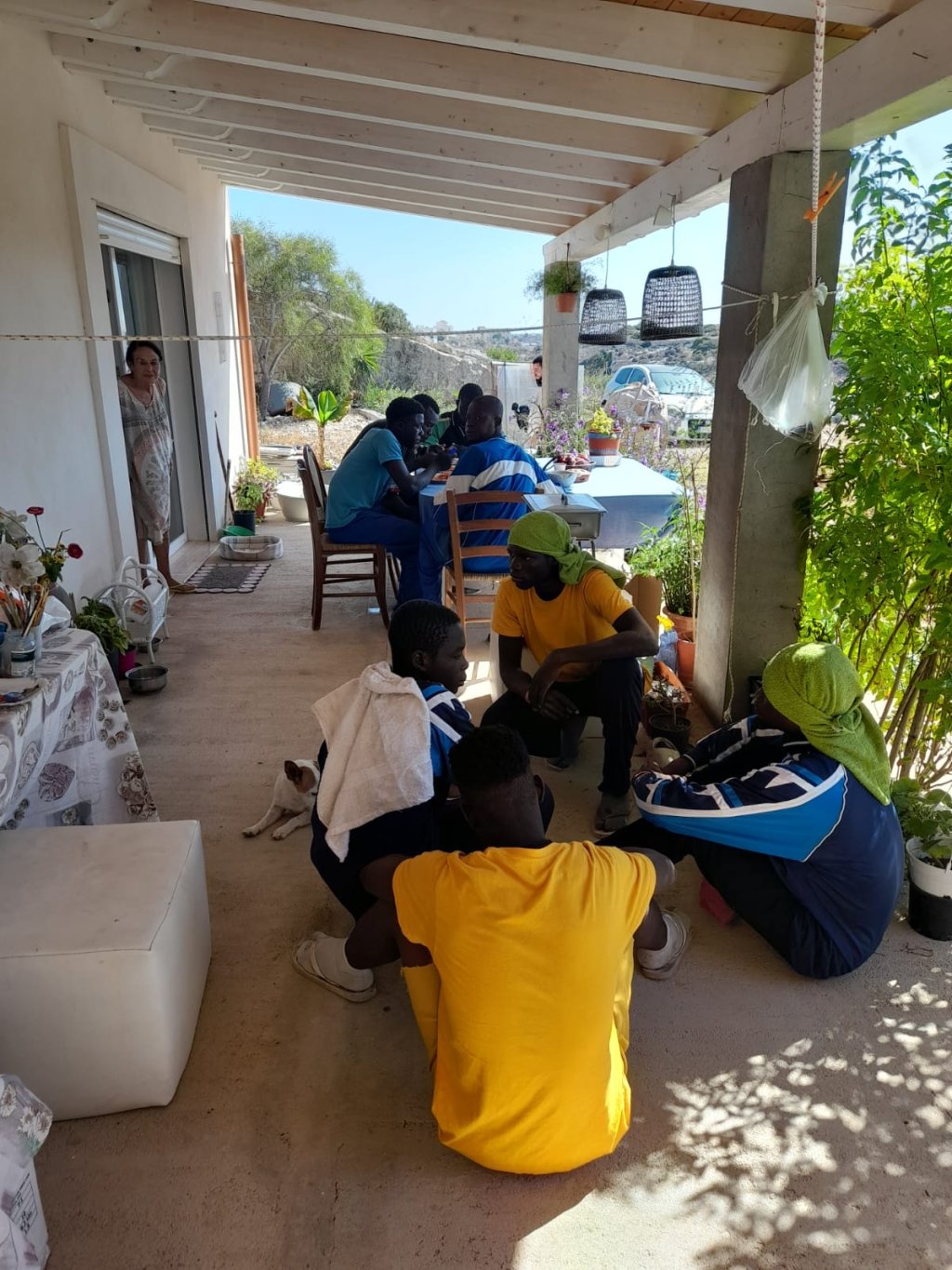 Young migrants from Burkina Faso gather to eat at Antonella Di Malta's house, his mother (Theresa) stands in the doorway to the terrace | Photo: Antonello di Malta / InfoMigrants