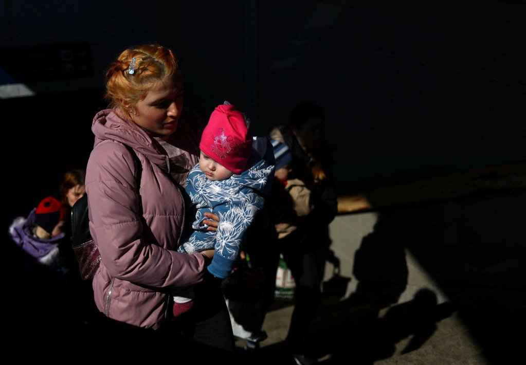 هانا مكاي  | لاجئة أوكرانية تحمل طفلها عبر محطة القطار في برزيميسل ، بولندا ، بعد فرارها من أوديسا في 21 مارس 2022. 