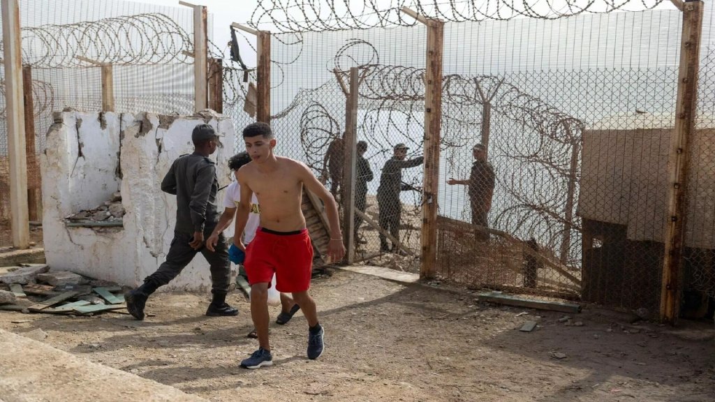 Moroccan forces keep guard at a breached fence at the frontier on Saturday, August 1 as a young man is returned from Ceuta to Morocco | Photo: AP Photo