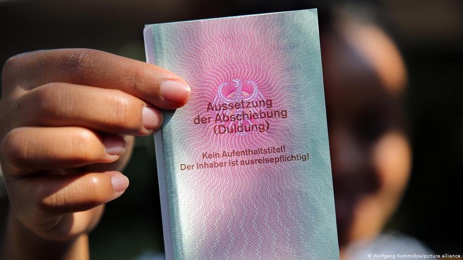 A refugee holds an identity card for refugees guaranteeing a suspension of deportation notice. This however is normally just a temporary solution for refugees hoping to stay in Germany | Photo: Wolfgang Kumm/dpa/picture-alliance